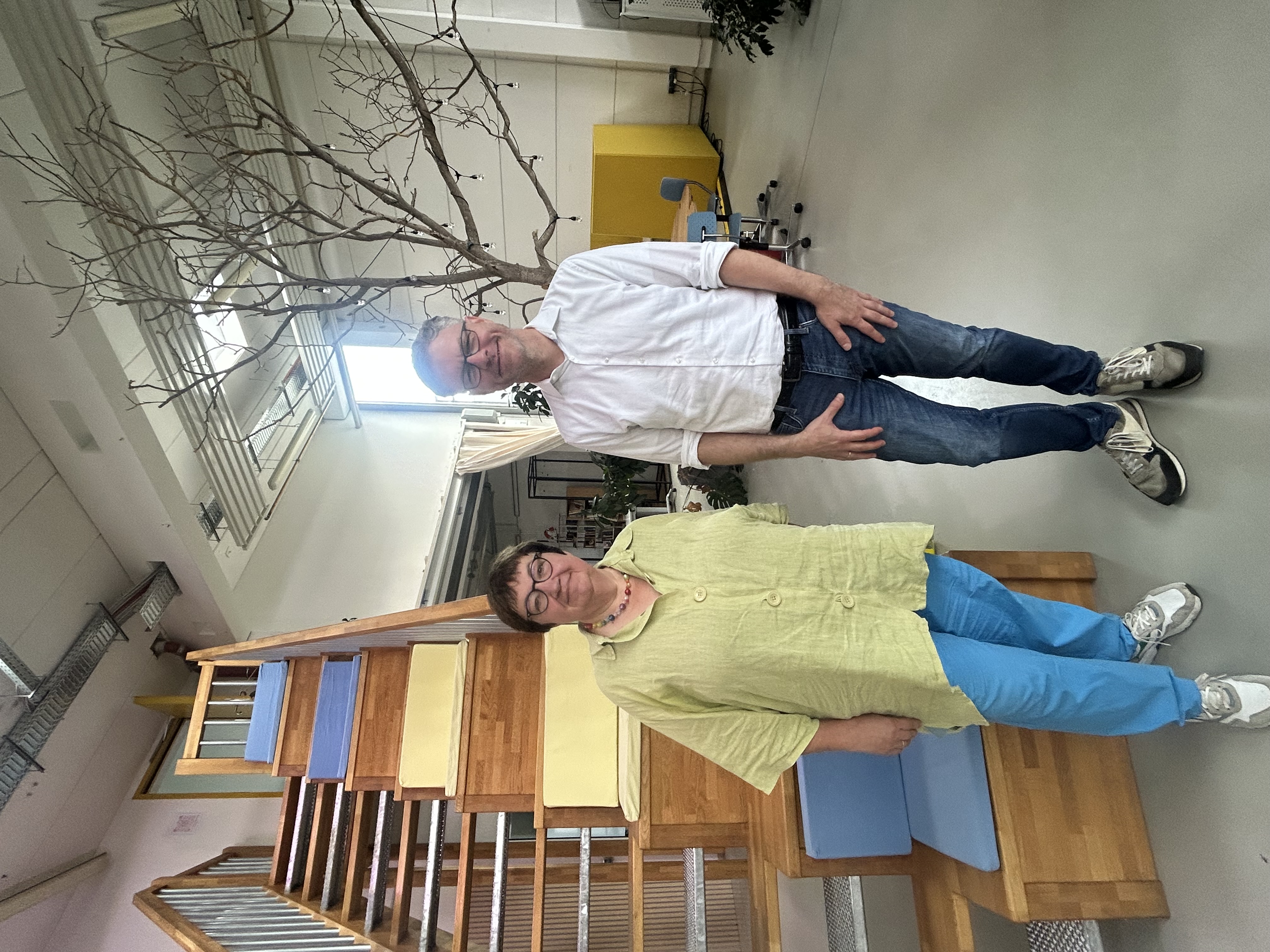 Elisabeth Herzog-von der Heide und Tobias Schröder vor einer Holztreppe in einem Baum in einer großen Halle.